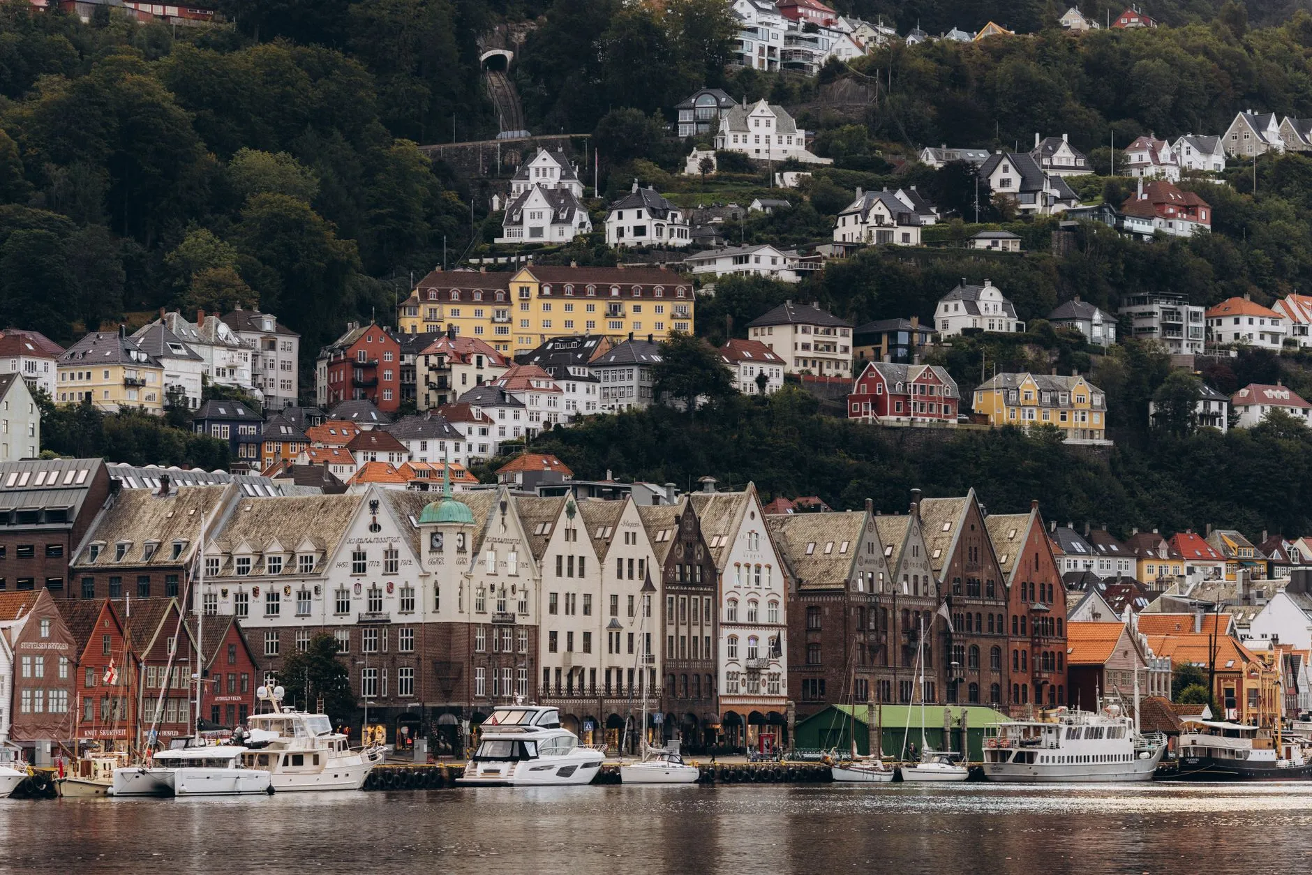 Scenic view of Bryggen and hillside houses in Bergen, Norway on a cloudy day.