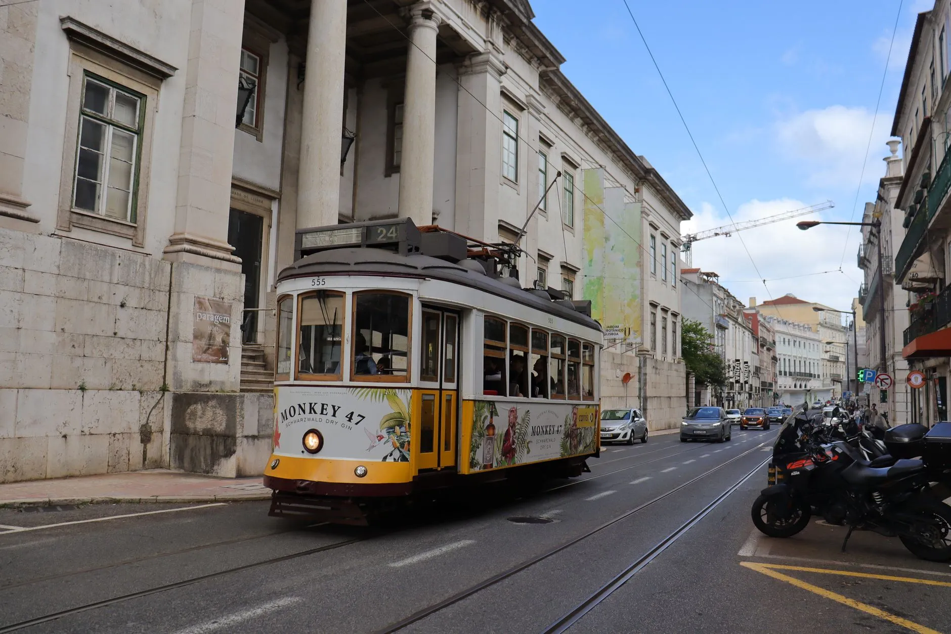 Charming vintage tram passing through historic streets of Lisbon, Portugal, on a sunny day.