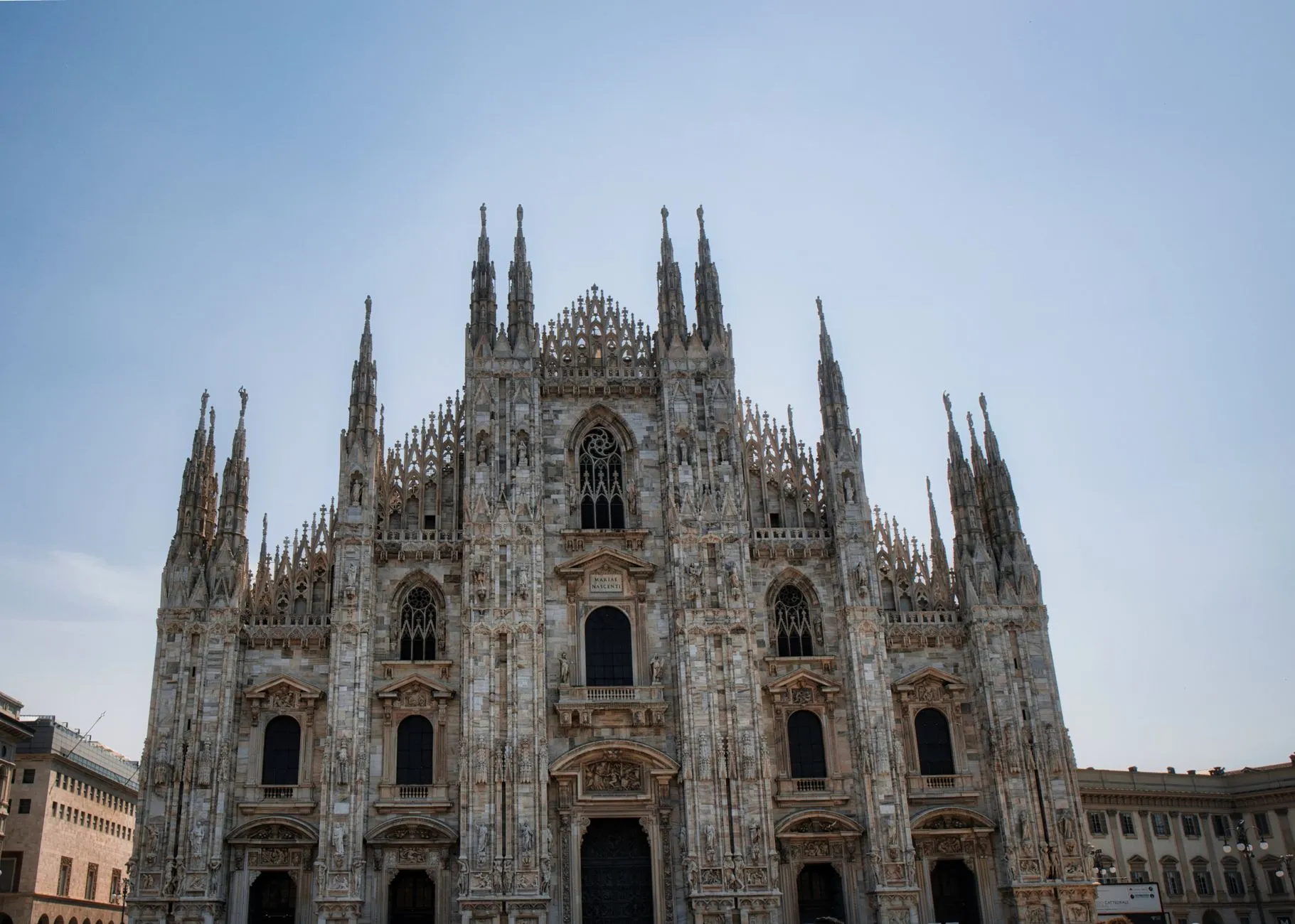 Capture of Milan Cathedral's intricate gothic facade under a clear blue sky in Milan, Italy.