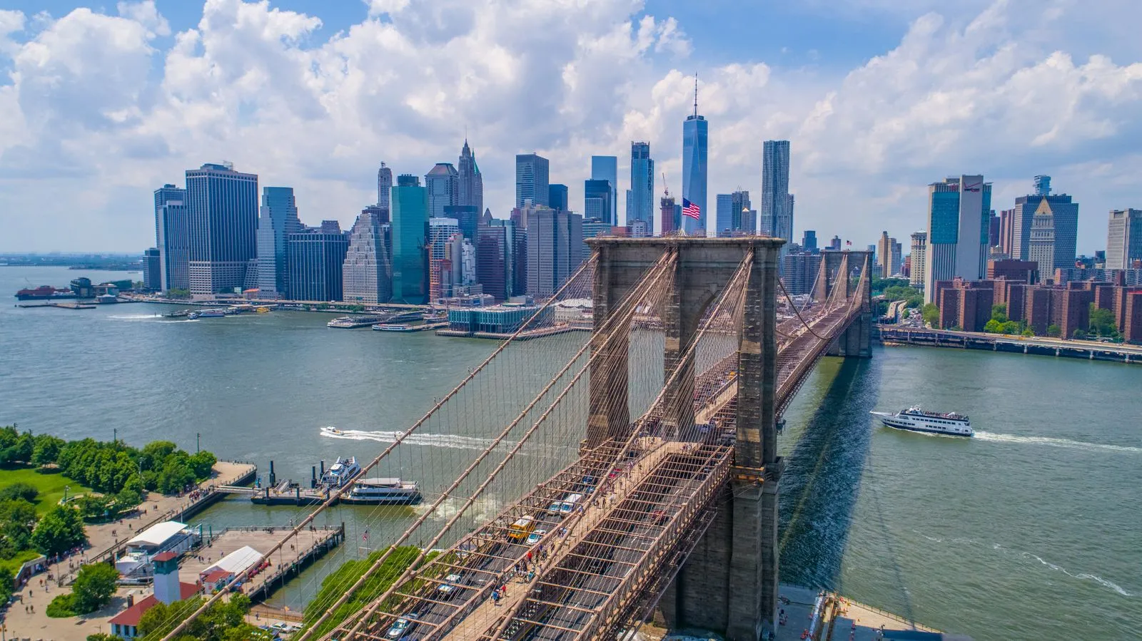 New York — the Brooklyn Bridge and the Lower Manhattan skyline with One World Trade Center under a blue sky