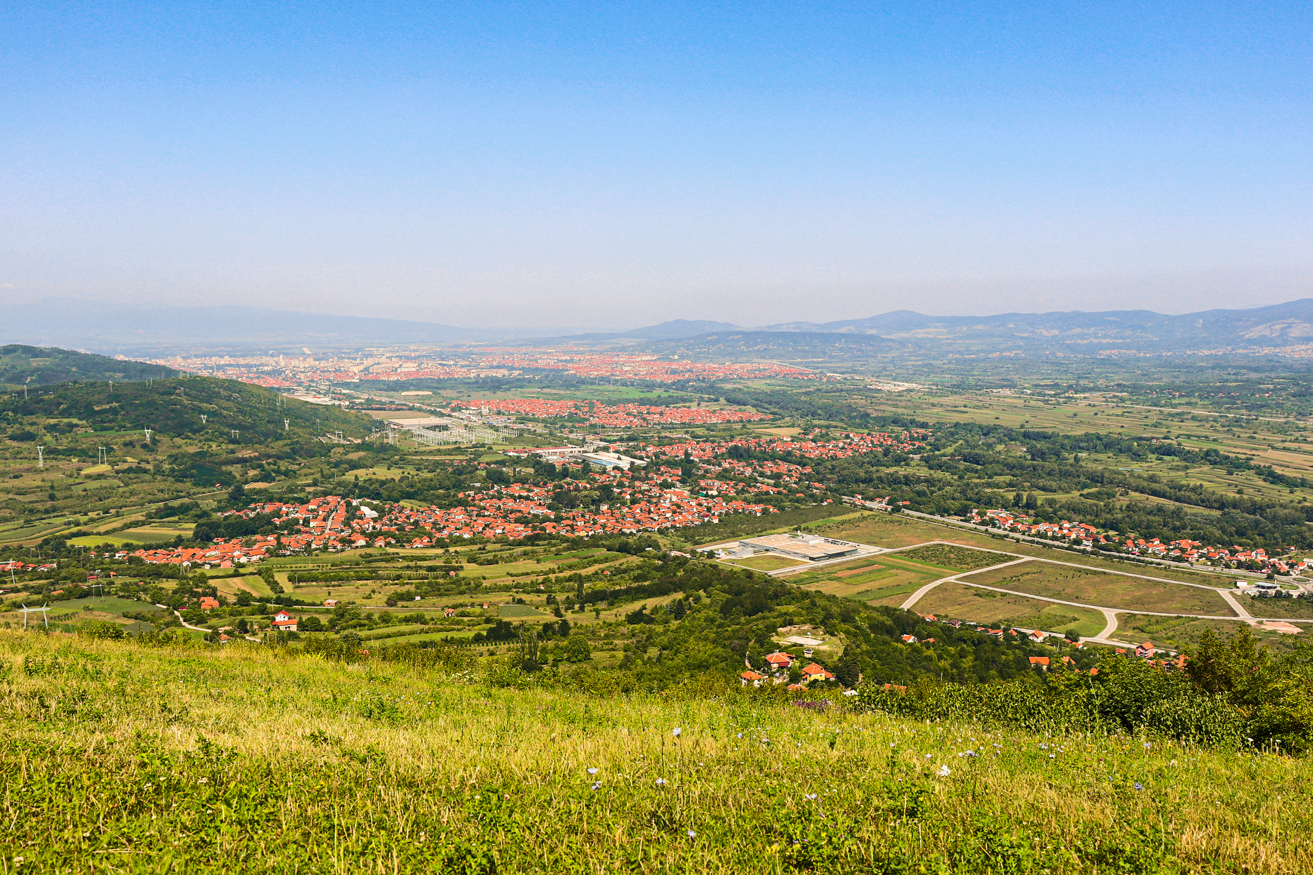 Nis, Serbia — Explore a breathtaking aerial view of the verdant Niš countryside in Serbia, captured under a clear blue sky.