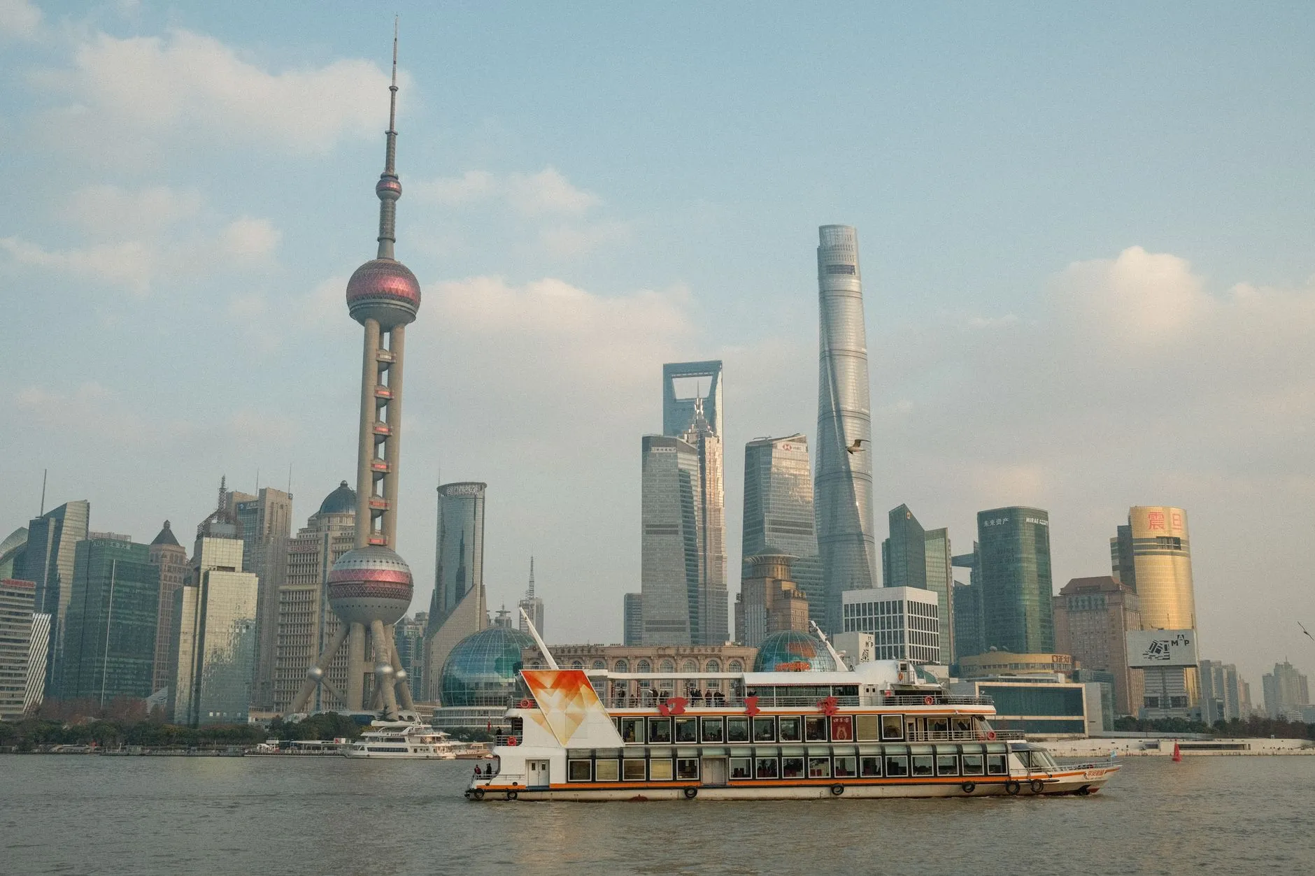 The Pudong skyline of Shanghai seen from the Bund, with the Oriental Pearl Tower, Shanghai Tower and a ferry on the Huangpu River.
