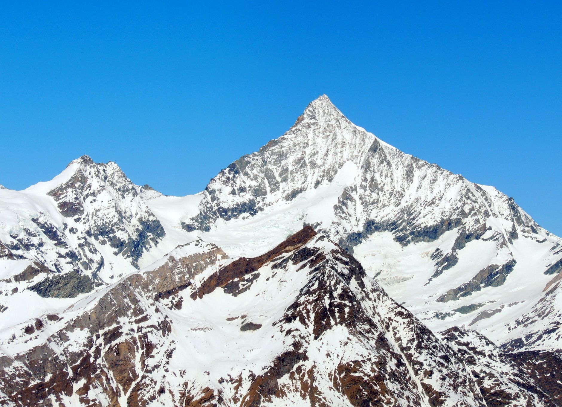 A sharp snow-capped peak in the Swiss Alps against a clear blue sky.